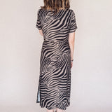 Person wearing a zebra print dress against a plain background