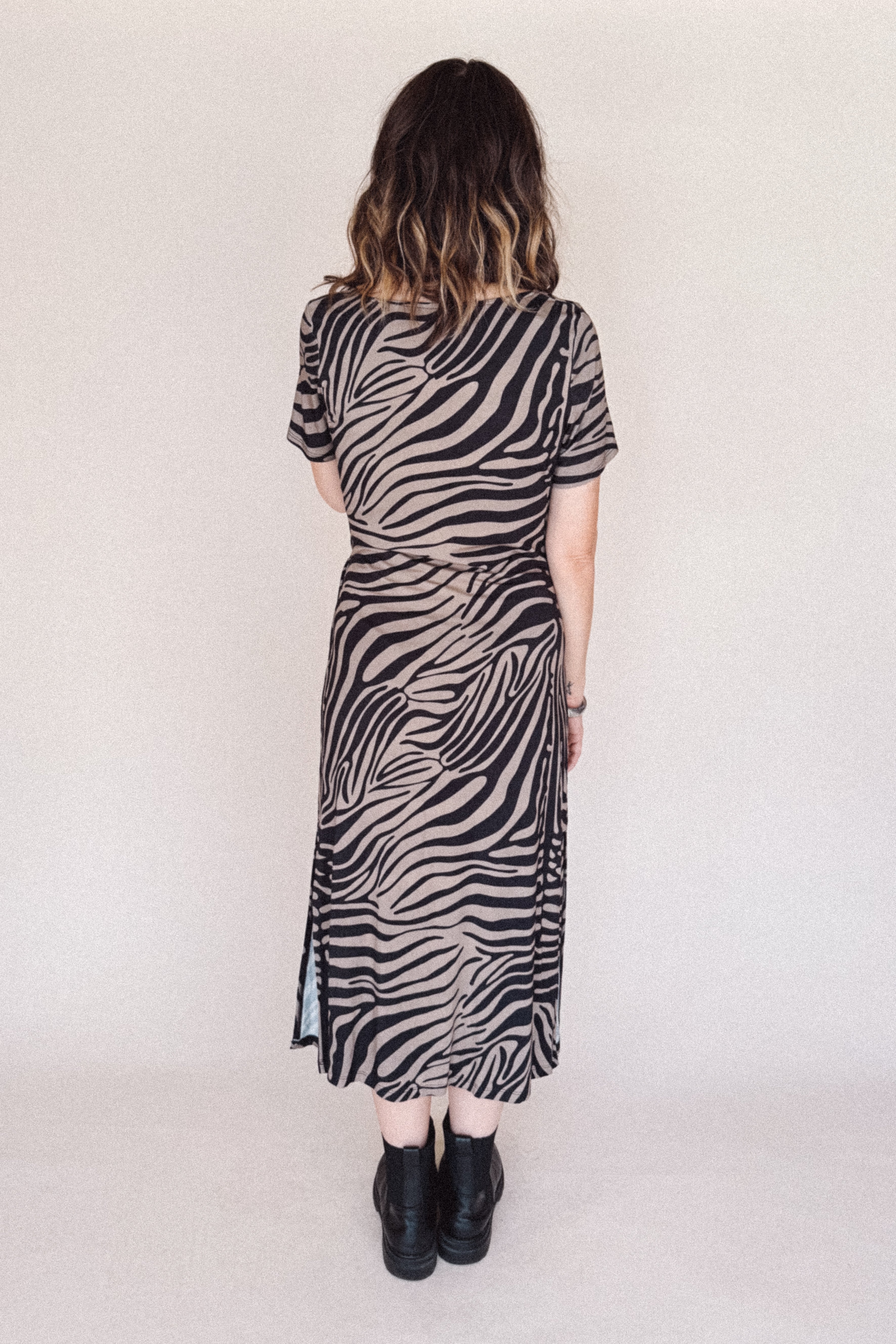Person wearing a zebra print dress against a plain background