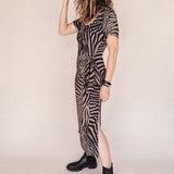 Person wearing a zebra print dress with a belt on a plain background