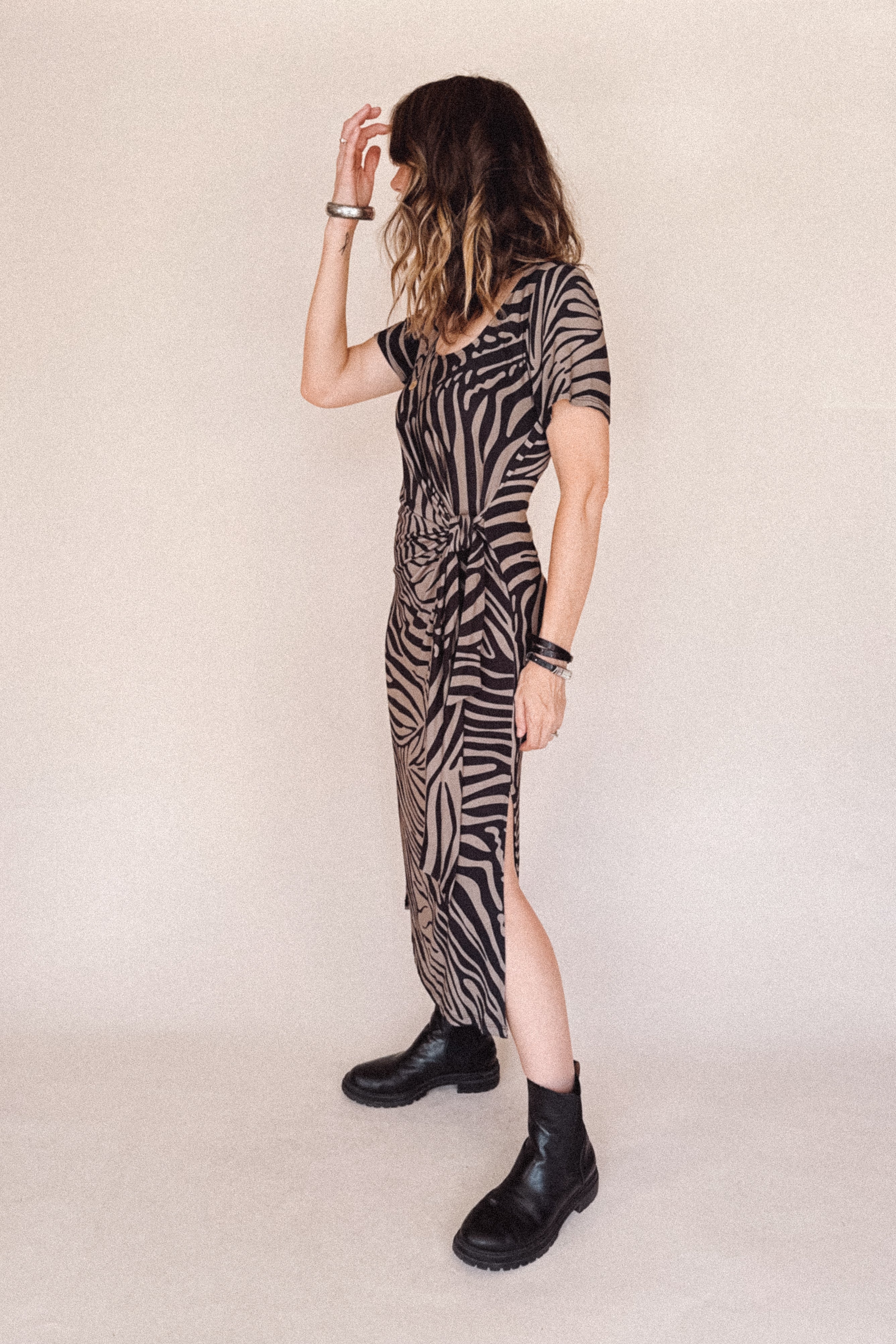 Person wearing a zebra print dress with a belt on a plain background