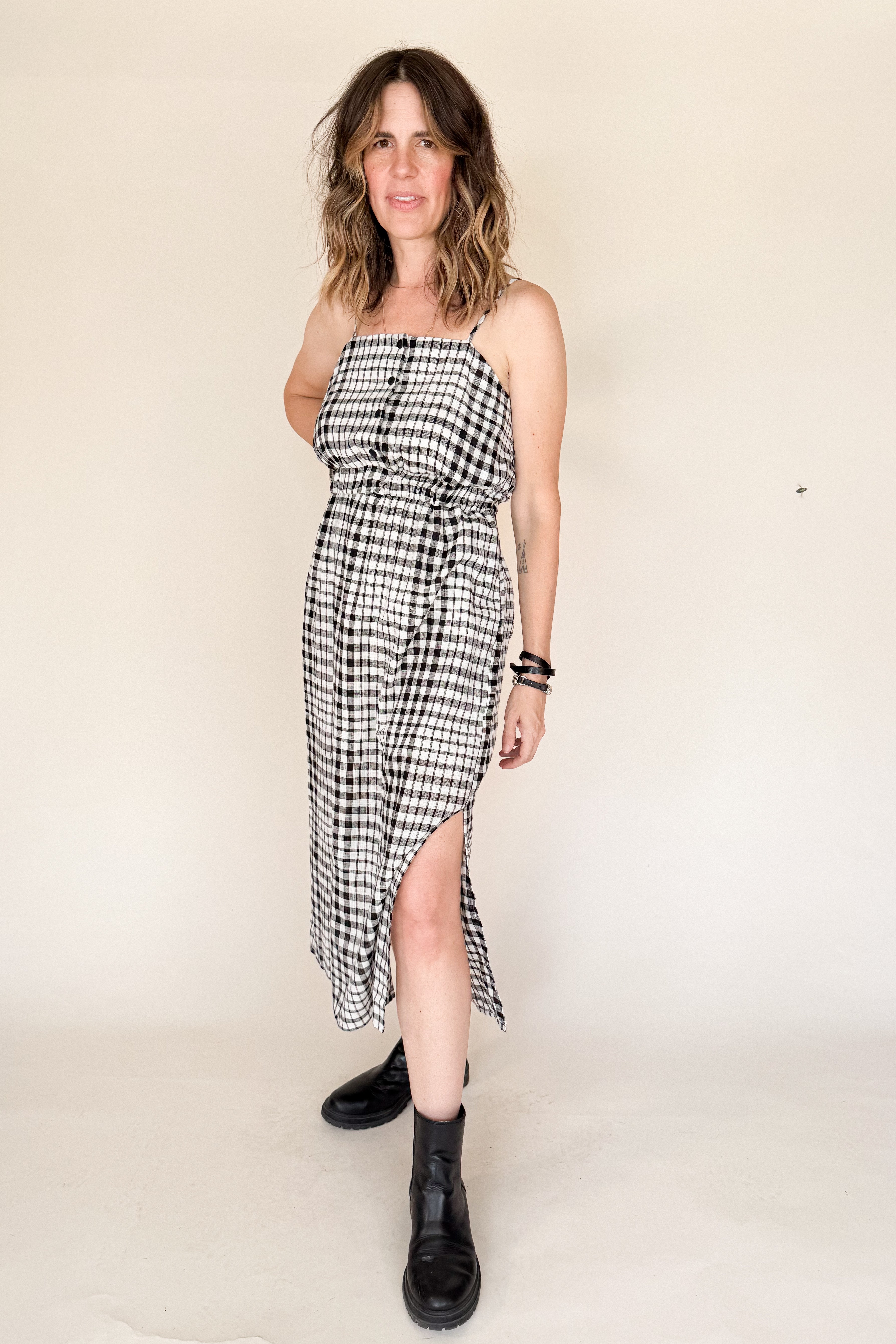 Woman wearing a black and white checkered dress with a slit on a beige background