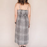 Person wearing a black and white checkered dress against a beige background
