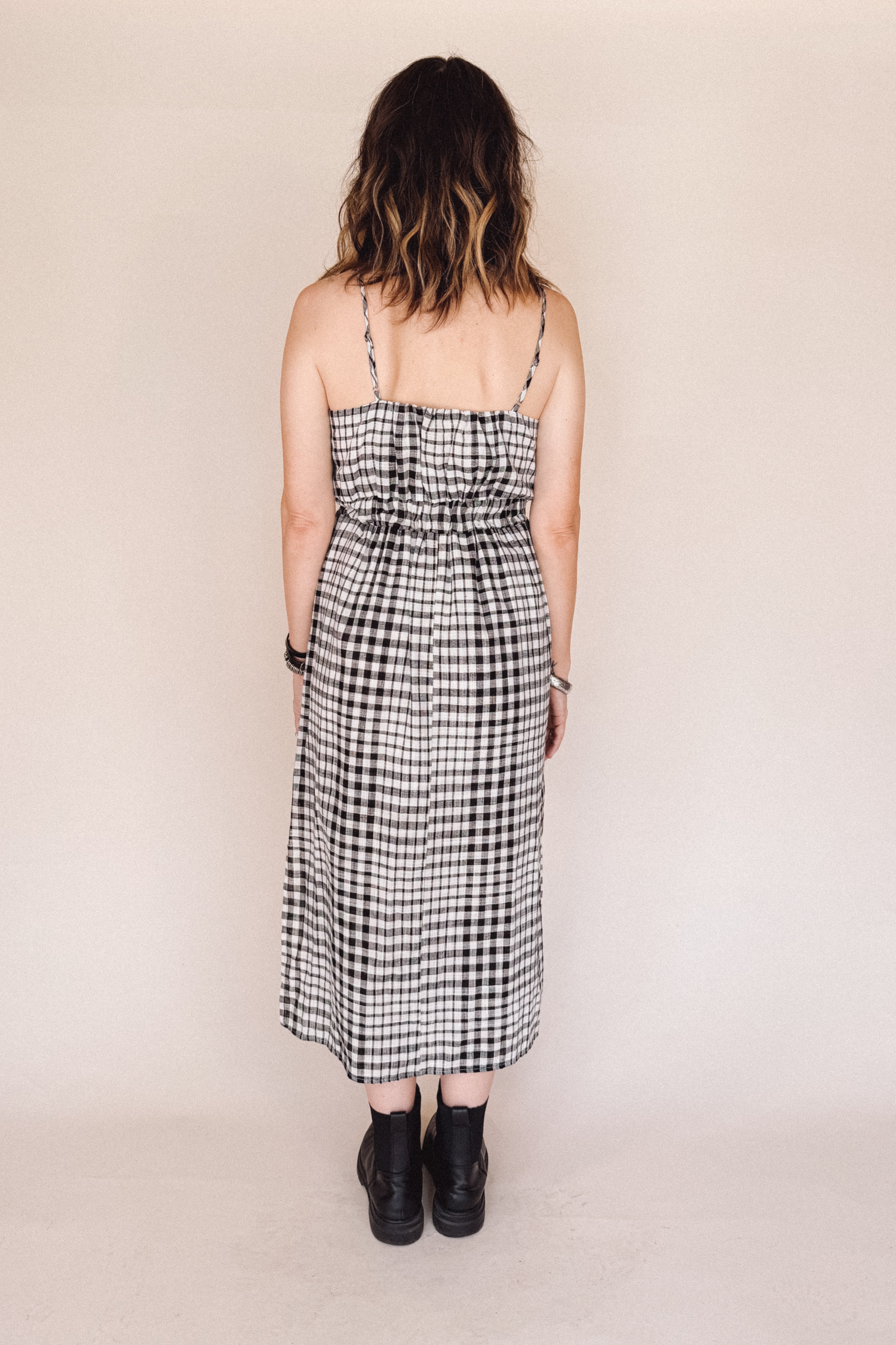 Person wearing a black and white checkered dress against a beige background