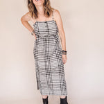 Woman wearing a black and white checkered dress against a beige background