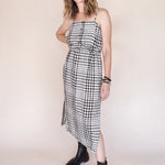 Woman wearing a black and white checkered dress with black boots on a plain background