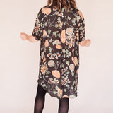 Woman wearing crane-print short sleeve button-up mini shirt dress with collar and side pockets, back