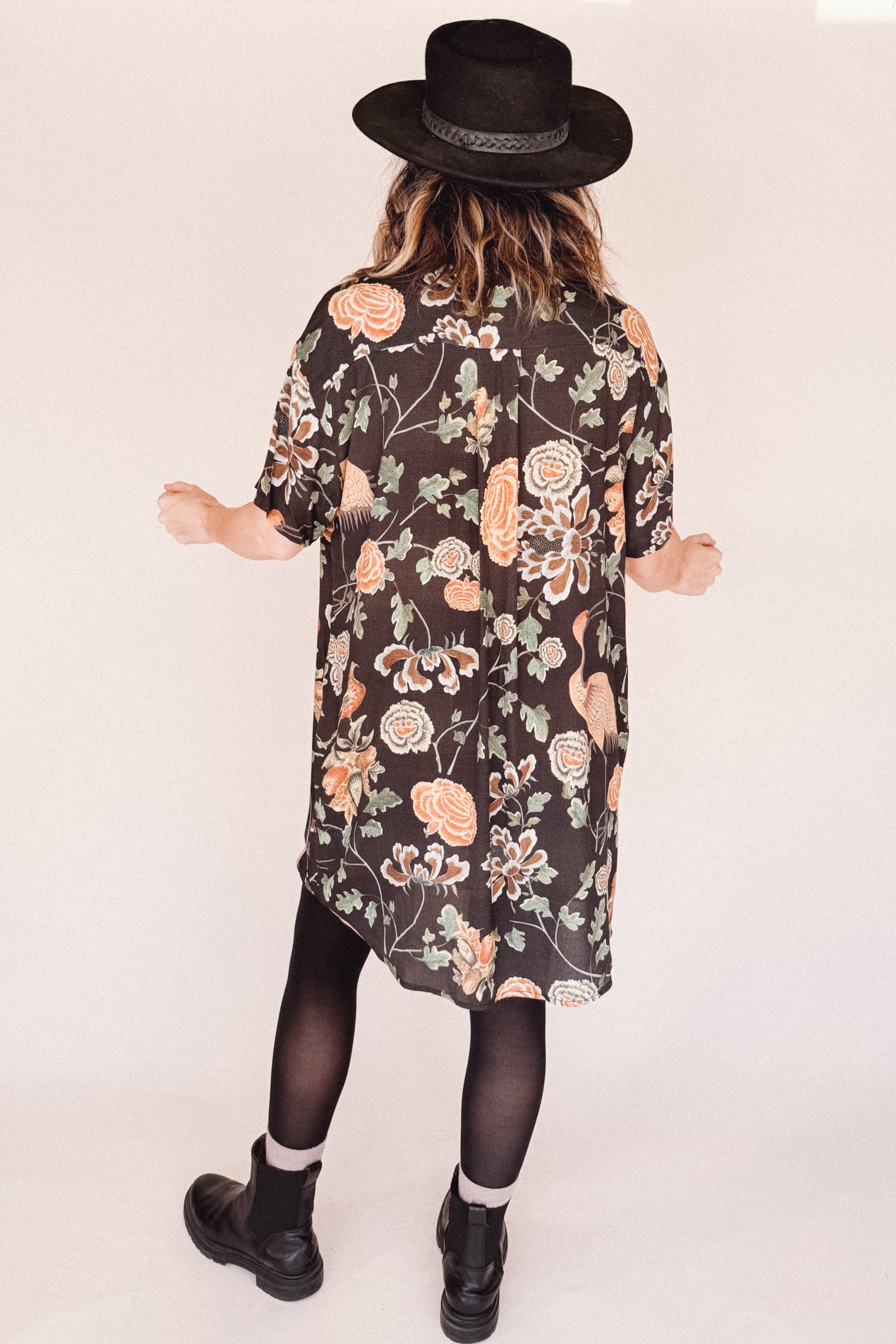 Woman wearing crane-print short sleeve button-up mini shirt dress with collar and side pockets, back