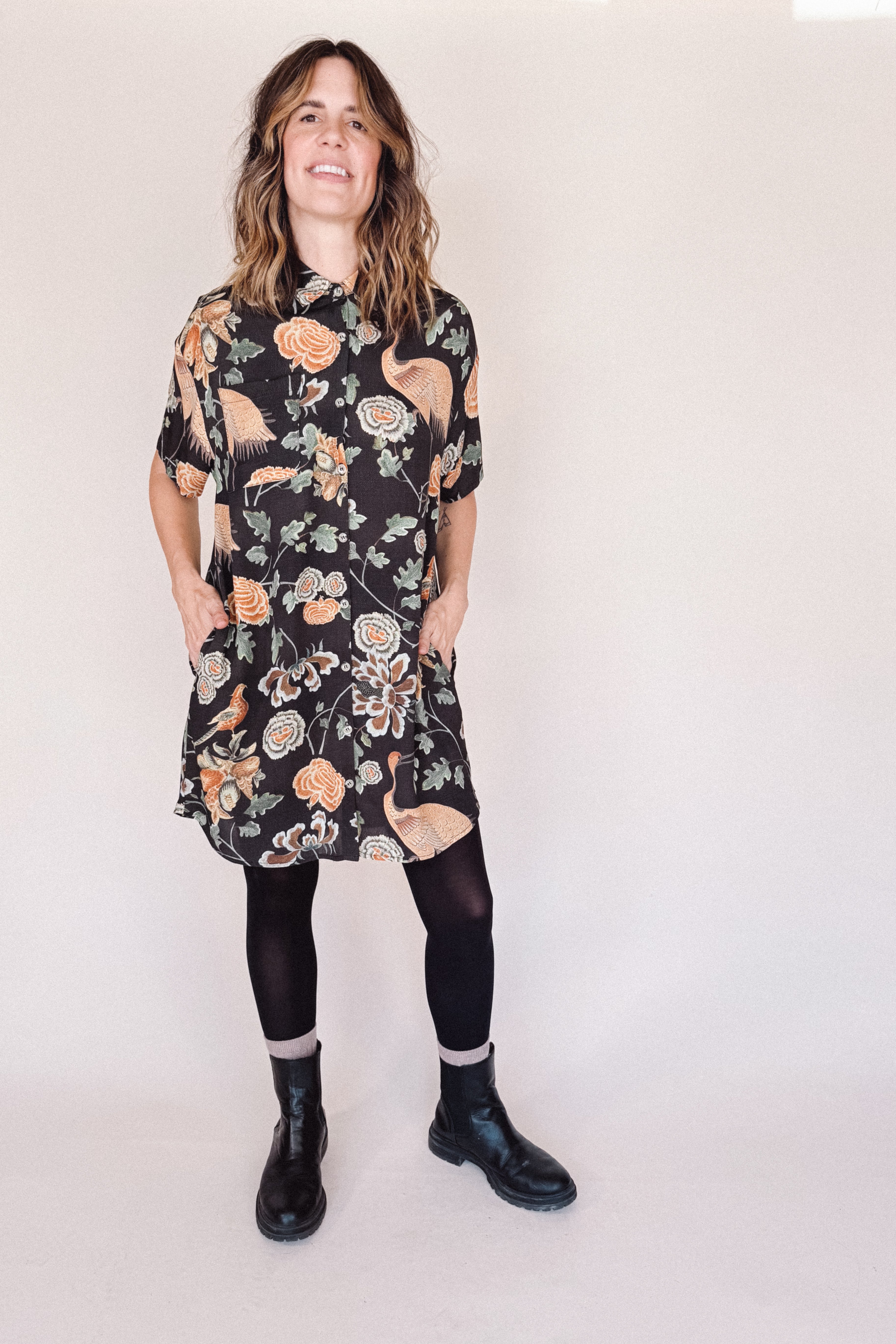 Woman wearing crane-print short sleeve button-up mini shirt dress with collar and side pockets