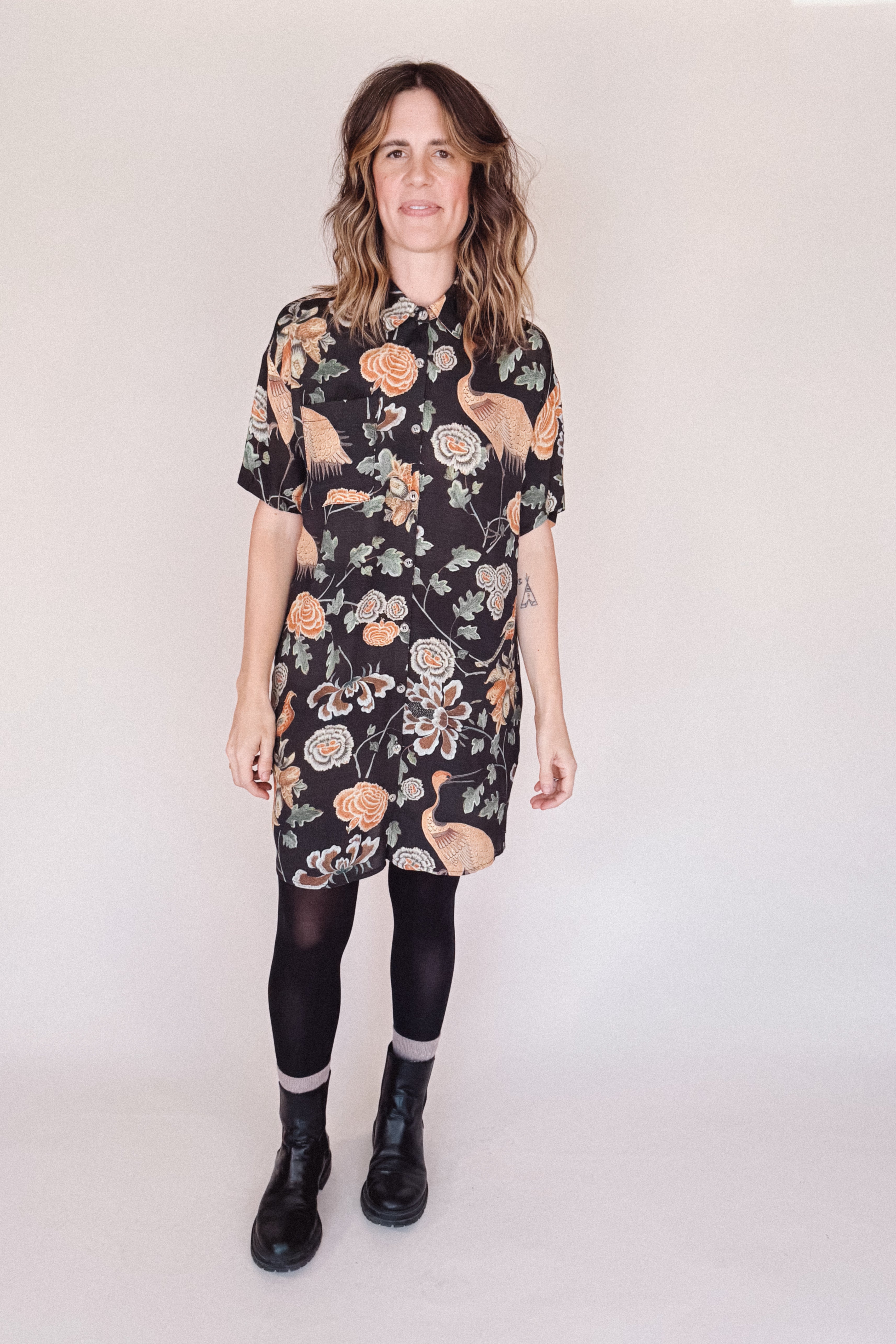 Woman wearing crane-print short sleeve button-up mini shirt dress with collar and side pockets