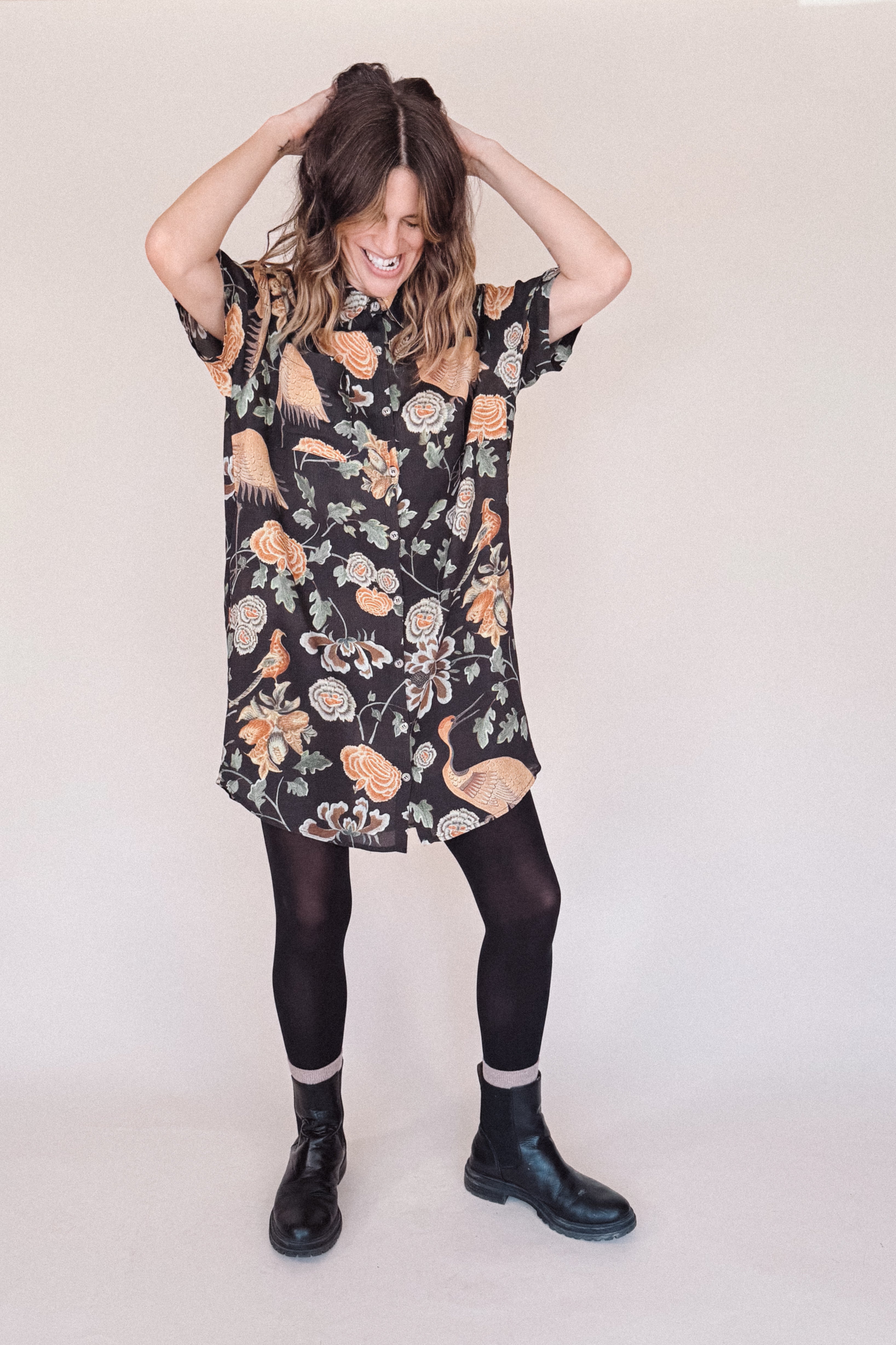 Woman wearing crane-print short sleeve button-up mini shirt dress with collar and side pockets
