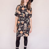 Woman wearing crane-print short sleeve button-up mini shirt dress with collar and side pockets with hat