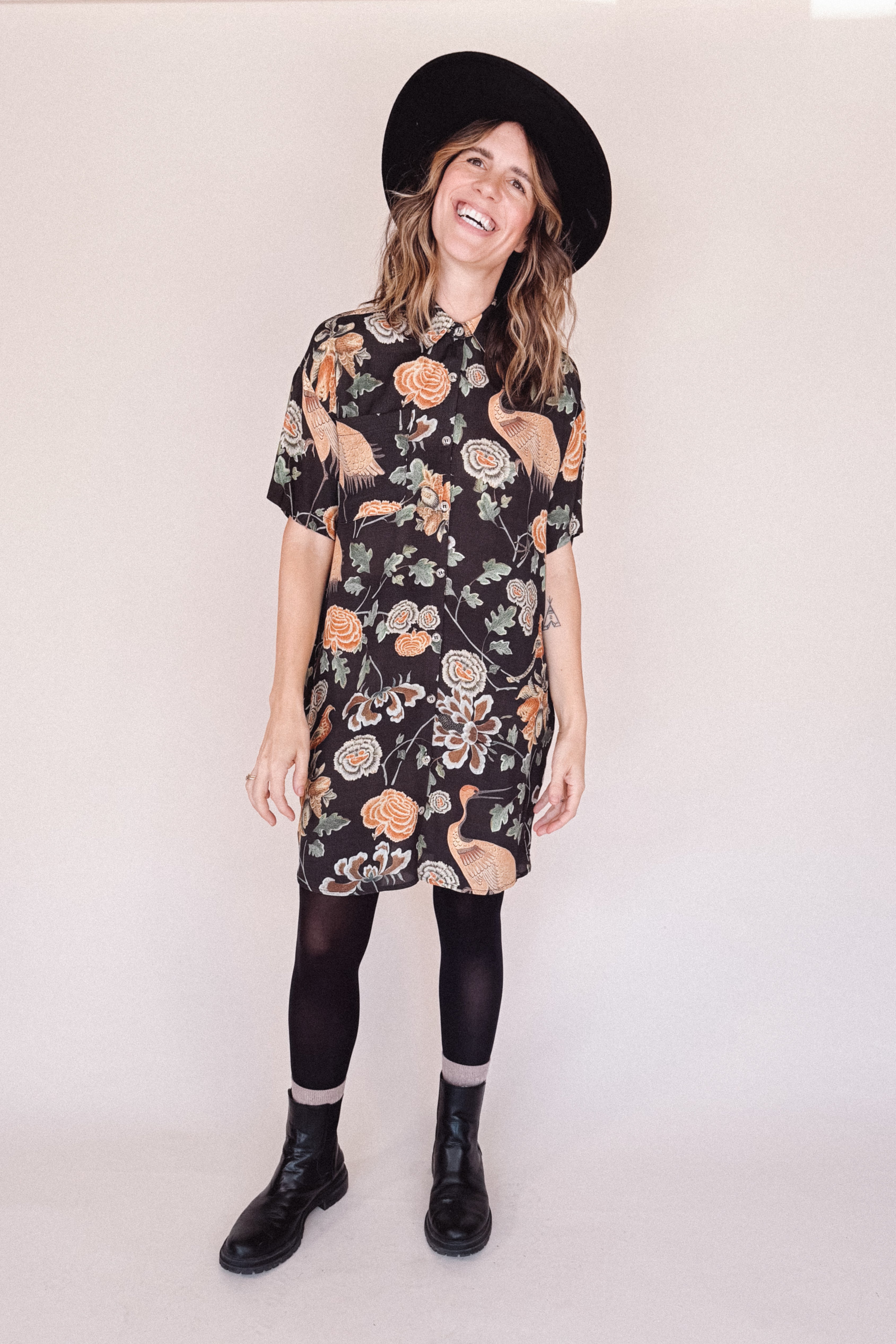 Woman wearing crane-print short sleeve button-up mini shirt dress with collar and side pockets with hat