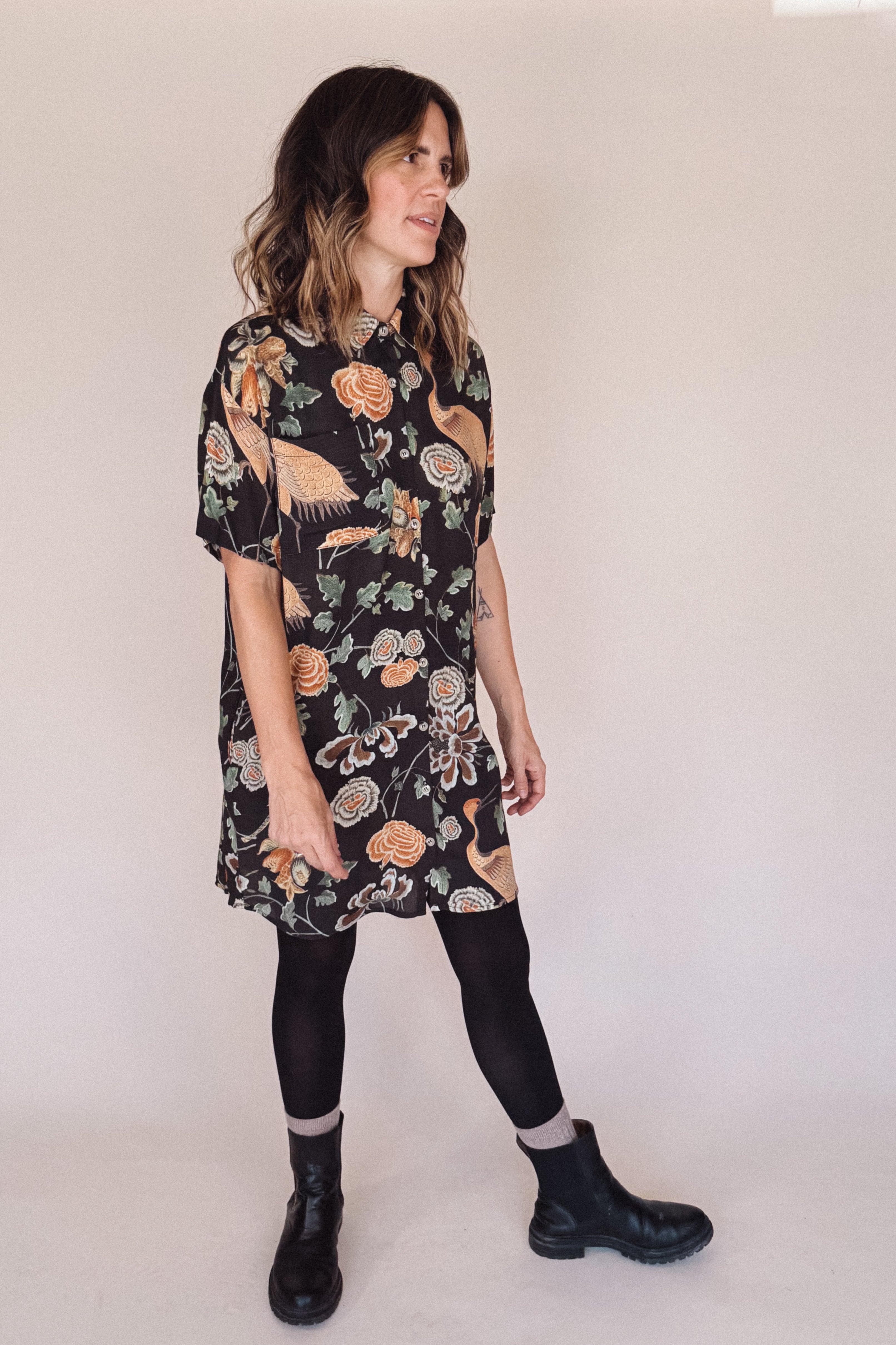 Woman wearing crane-print short sleeve button-up mini shirt dress with collar and side pockets