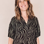 Woman wearing a black and olive zebra pattern dress on a beige background