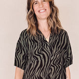 Woman wearing a black and olive zebra pattern dress on a beige background