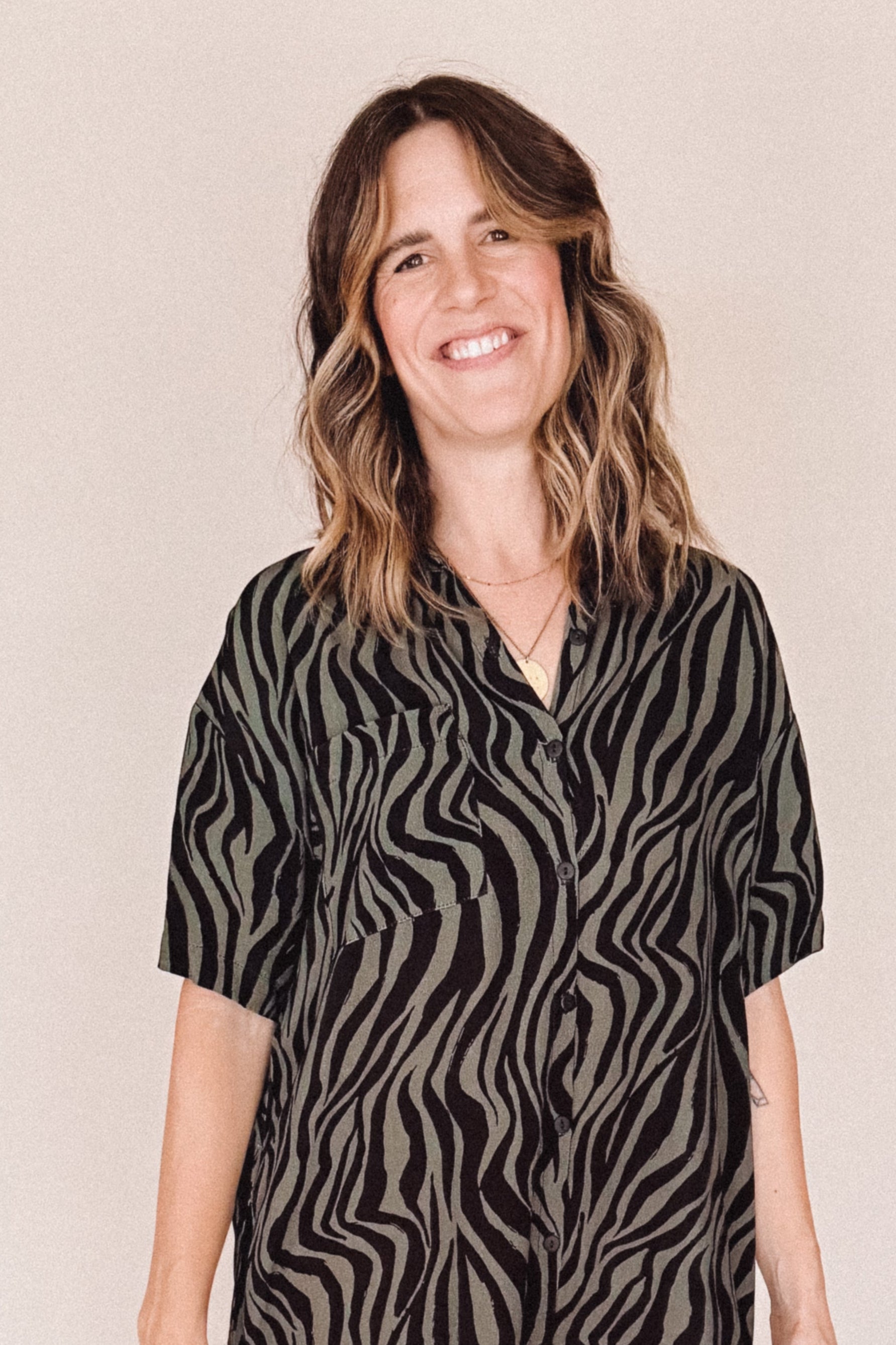 Woman wearing a black and olive zebra pattern dress on a beige background