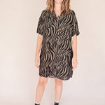 Woman wearing a zebra pattern dress on a beige background