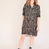 Person wearing a zebra patterned dress on a plain background