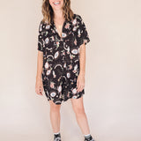 Woman in printed short sleeve button-up mini shirt dress with collar, breast pocket and side-seam pockets