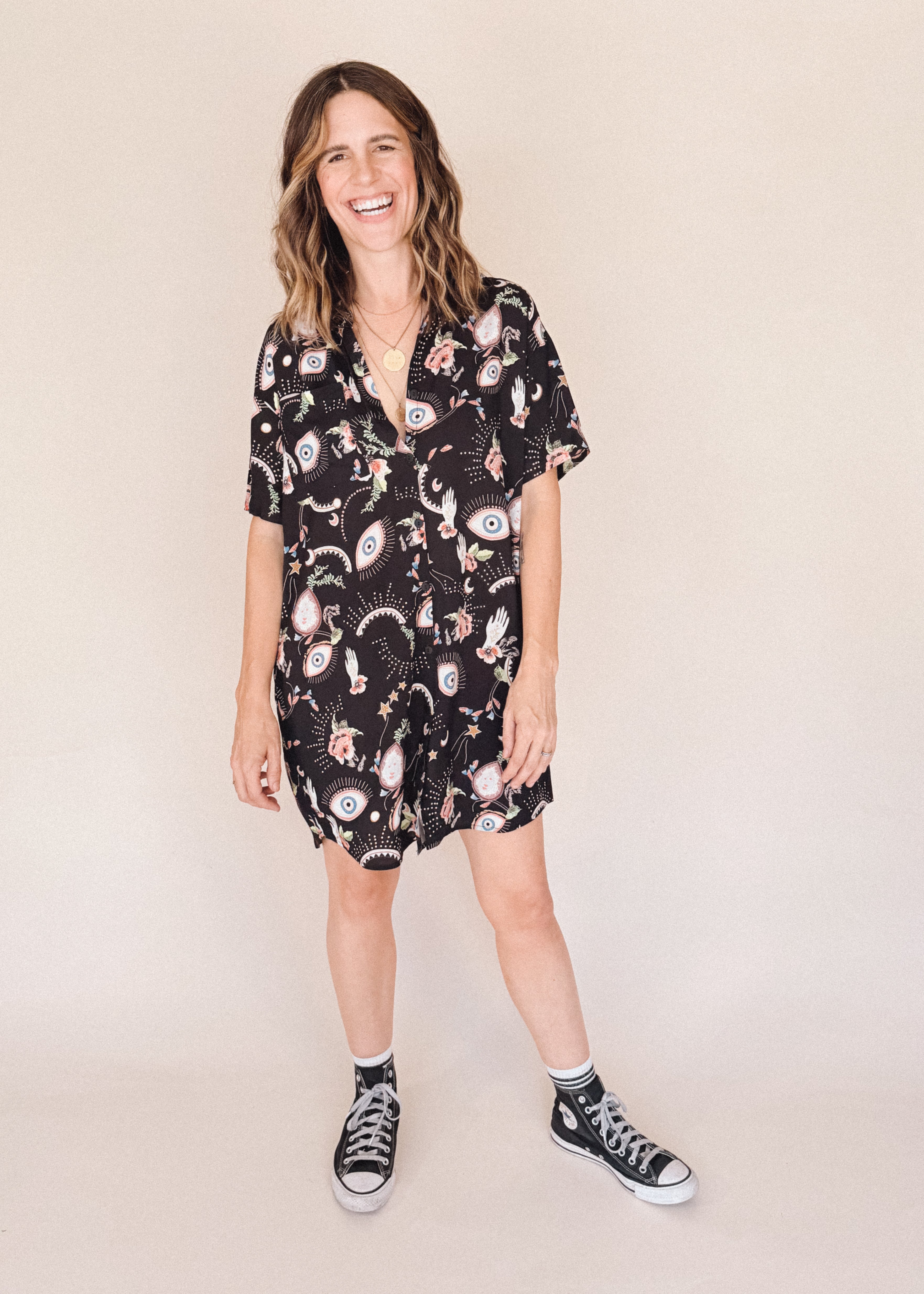 Woman in printed short sleeve button-up mini shirt dress with collar, breast pocket and side-seam pockets