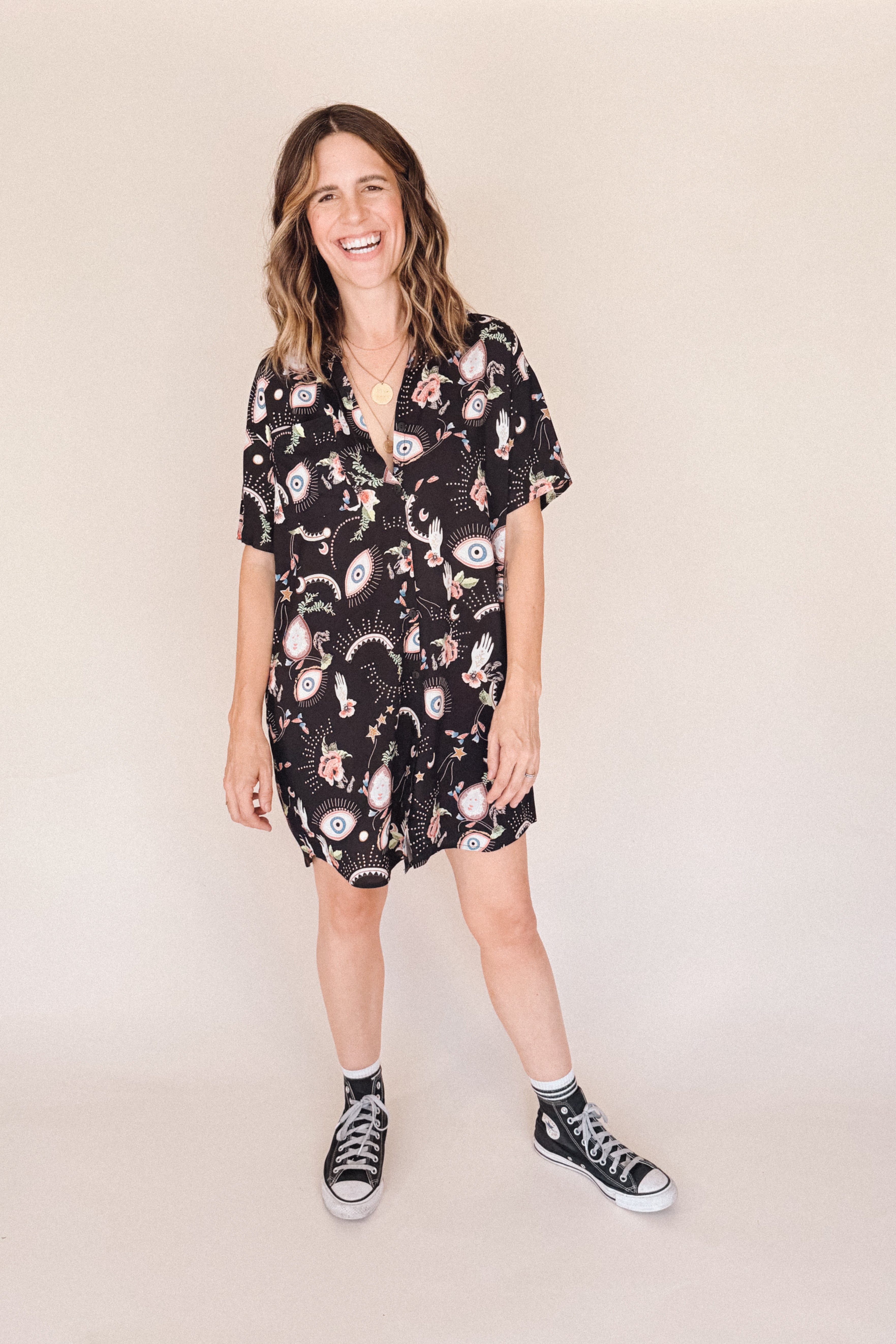 Woman in printed short sleeve button-up mini shirt dress with collar, breast pocket and side-seam pockets