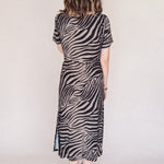 Person wearing a zebra print dress against a plain background
