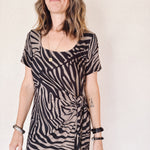 Woman wearing a zebra print dress against a plain background
