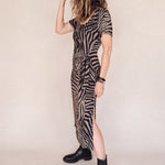 Person wearing a zebra print dress with a belt on a plain background