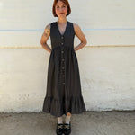Person wearing a black dress standing on a white and gray pavement.