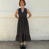 Person wearing a black dress standing on a white and gray pavement.