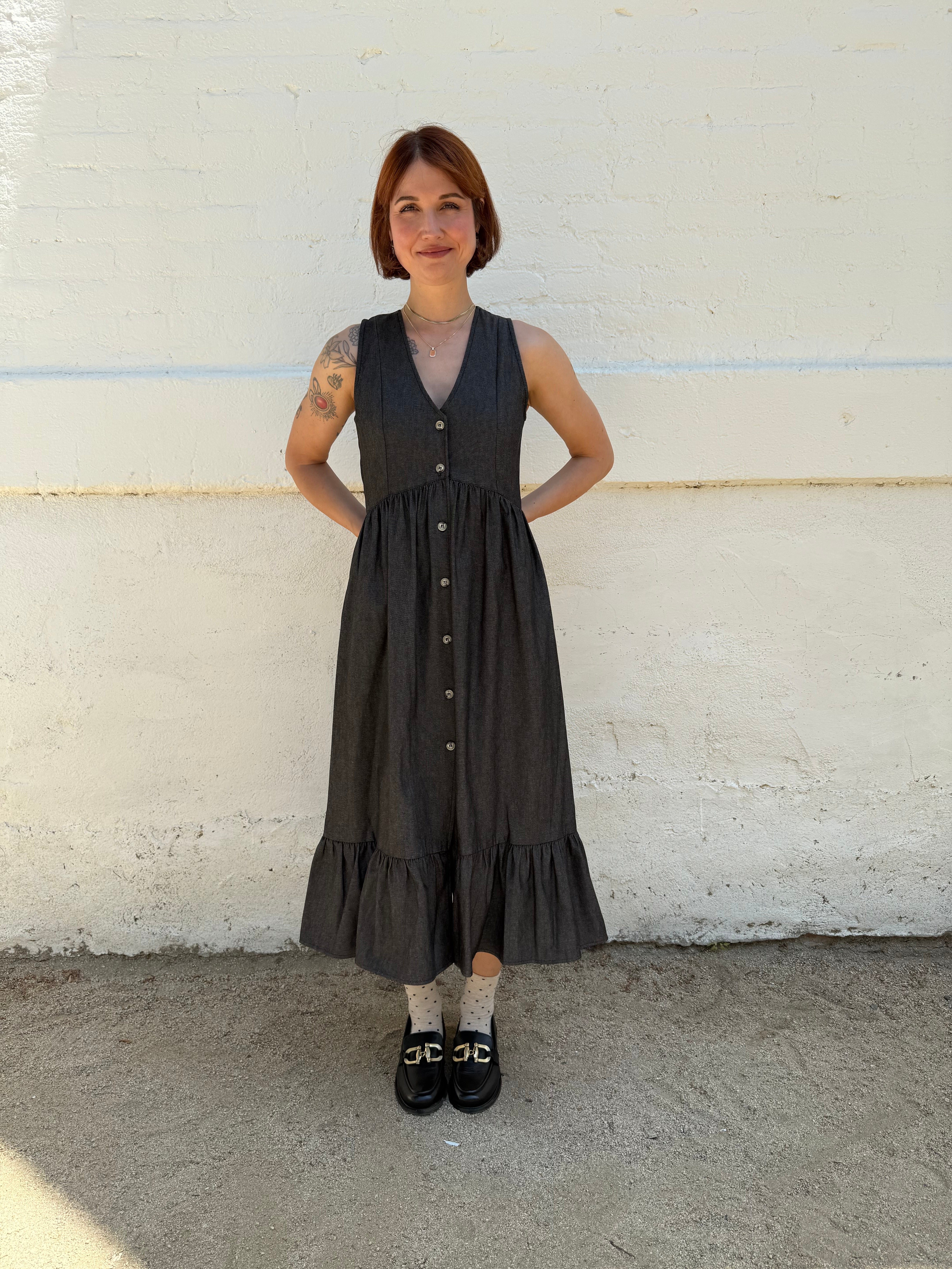 Person wearing a black dress standing on a white and gray pavement.