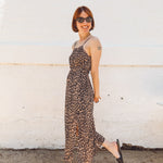 girl wearing leopard elastic waist spaghetti strap midid dress with side slits and sticking out her tongue
