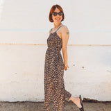 girl wearing leopard elastic waist spaghetti strap midid dress with side slits and sticking out her tongue
