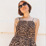 close up view of short haired girl wearing spaghetti strap button front elastic waist midid dress in leopard print crepe georgette.