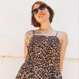 close up view of short haired girl wearing spaghetti strap button front elastic waist midid dress in leopard print crepe georgette.