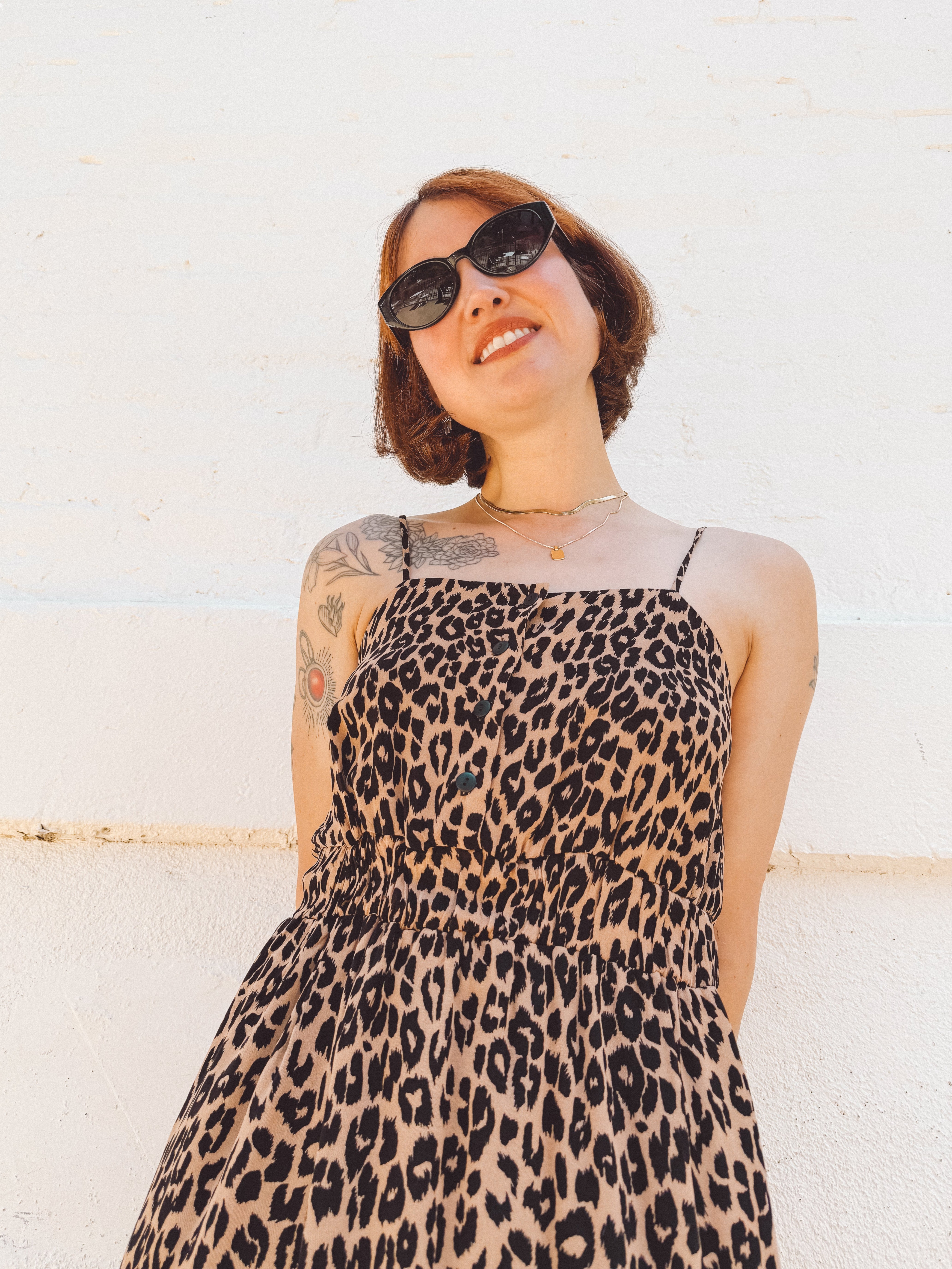 close up view of short haired girl wearing spaghetti strap button front elastic waist midid dress in leopard print crepe georgette.