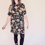 Woman wearing crane-print short sleeve button-up mini shirt dress with collar and side pockets twirling around