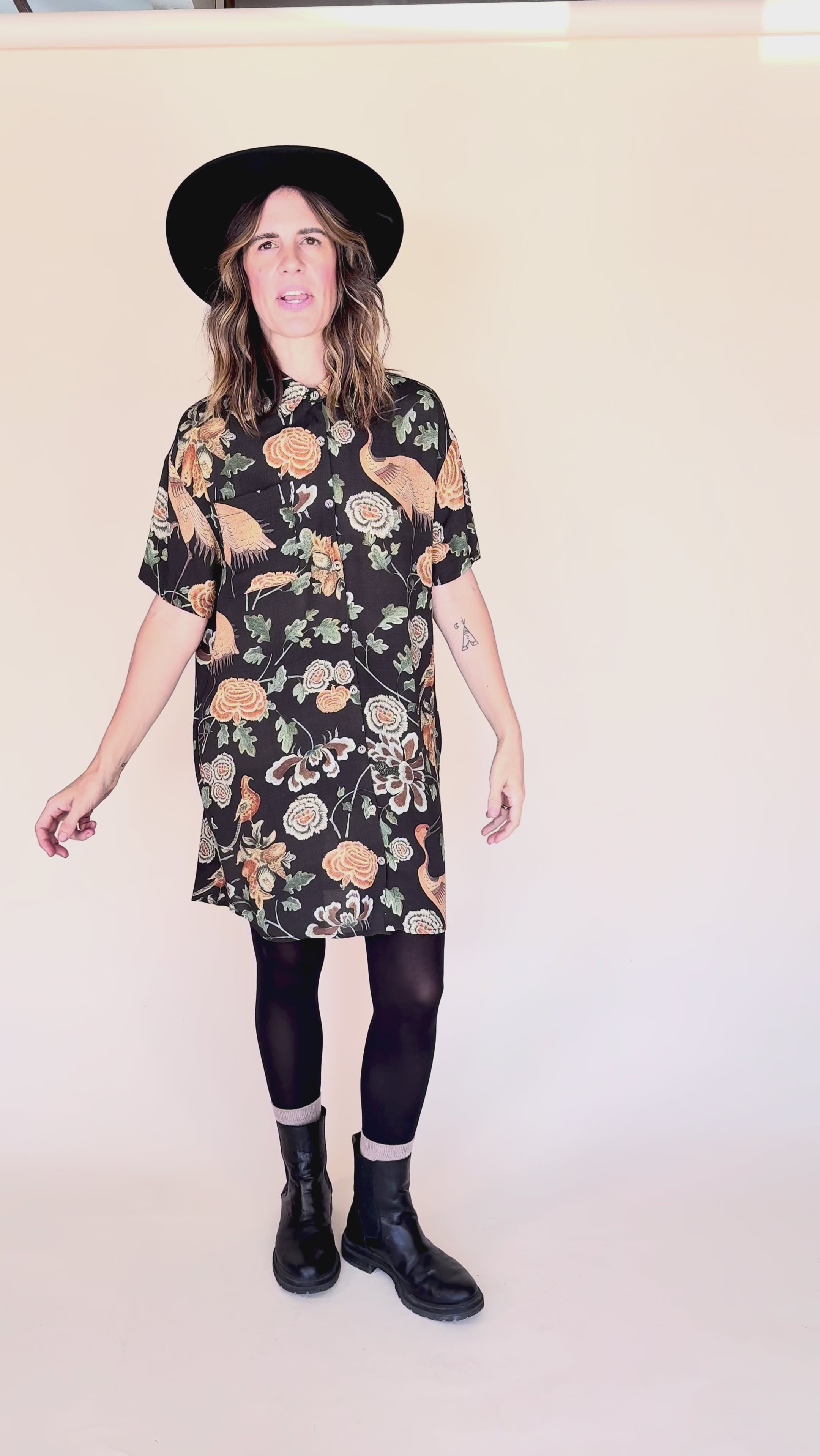 Woman wearing crane-print short sleeve button-up mini shirt dress with collar and side pockets twirling around